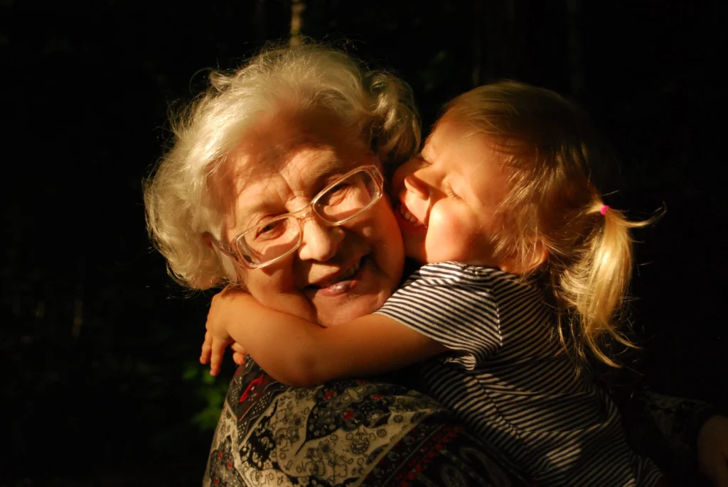 Little girl with blonde hair hugs her grandmother who receives personal care services at home