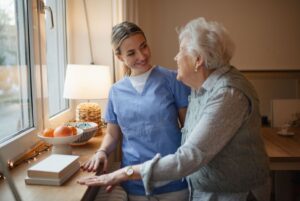 Home caregiver helps elderly woman in her home