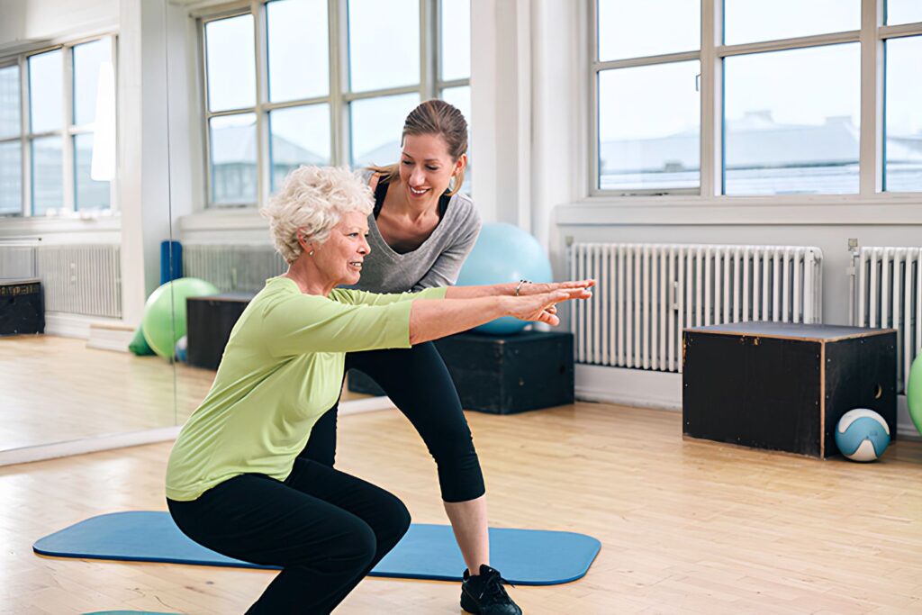 Fitness coach helping a woman with leg exercises for seniors