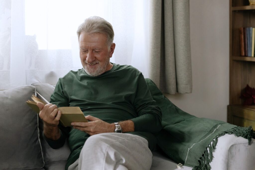 Elderly man sitting reading a book at home as he enjoys affordable senior care at home
